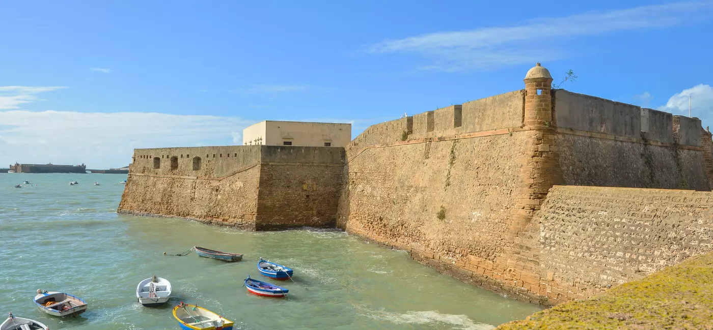 A stone fortress overlooking a quiet bay with empty fishing boats
