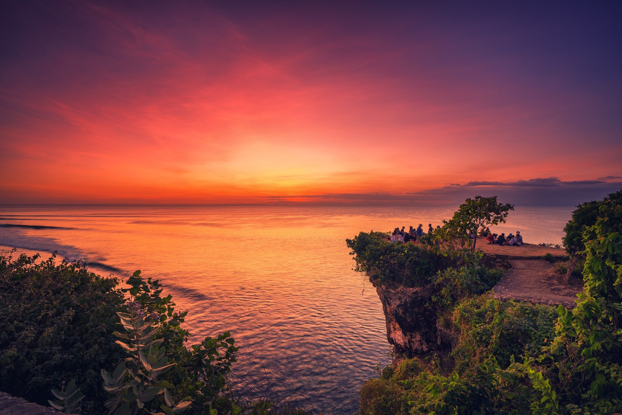 Bali, South Kuta, Badung - Indonesia - Mart 9, 2022: Travel people seating on the top mountain cliff on Balangan Beach and enjoy beautiful sunset. Bali, Indonesia
