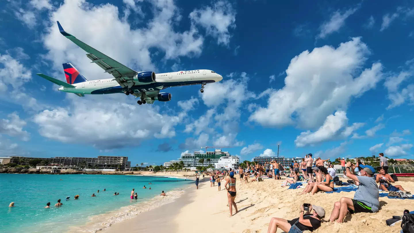 The commercial jet Delta Air Lines approaches Princess Juliana airport above onlooking spectators in Maho beach, Sint Maarten