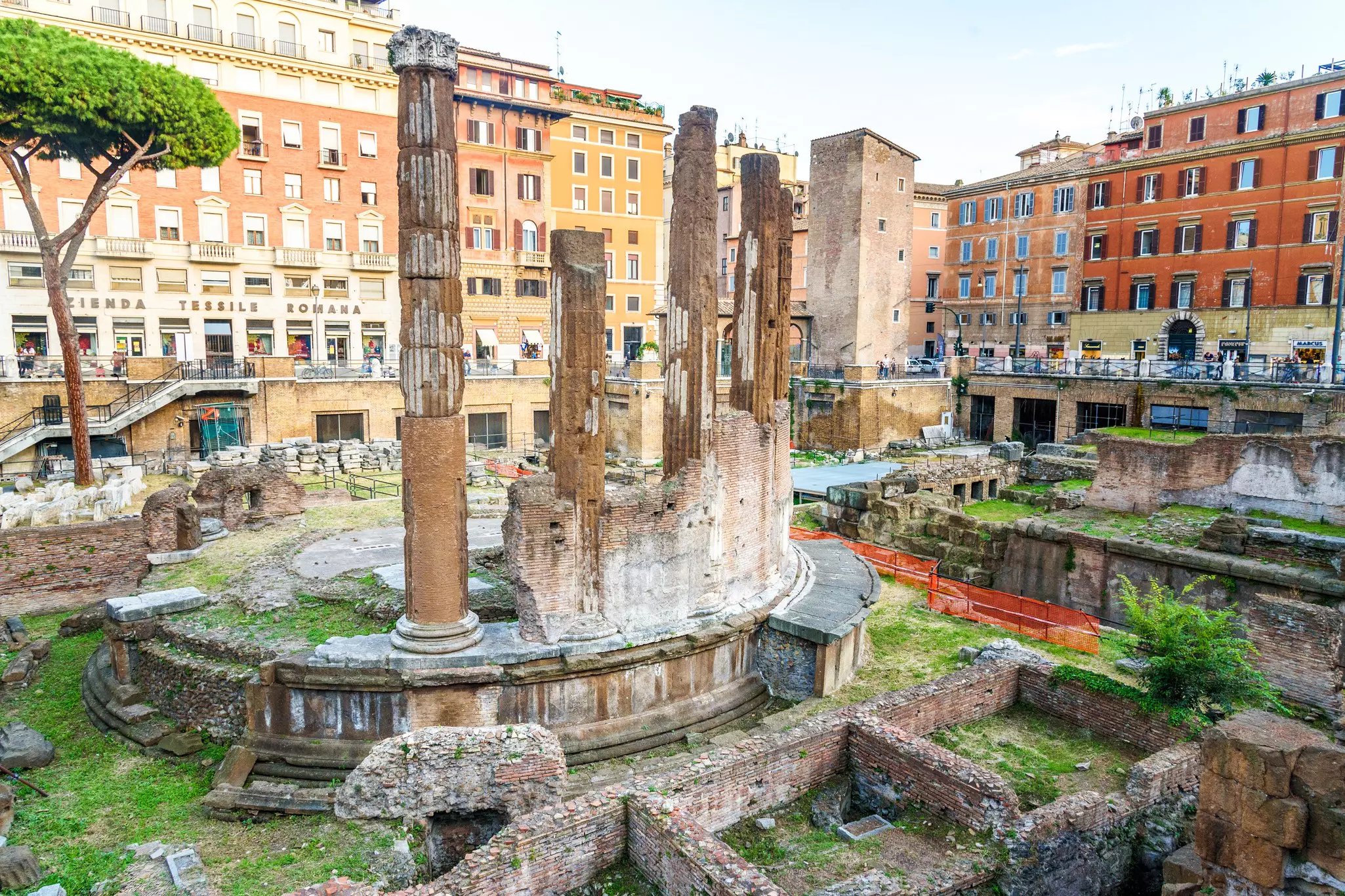 Ancient columns are seen at an archaeological site surrounded by modern buildings in a city.