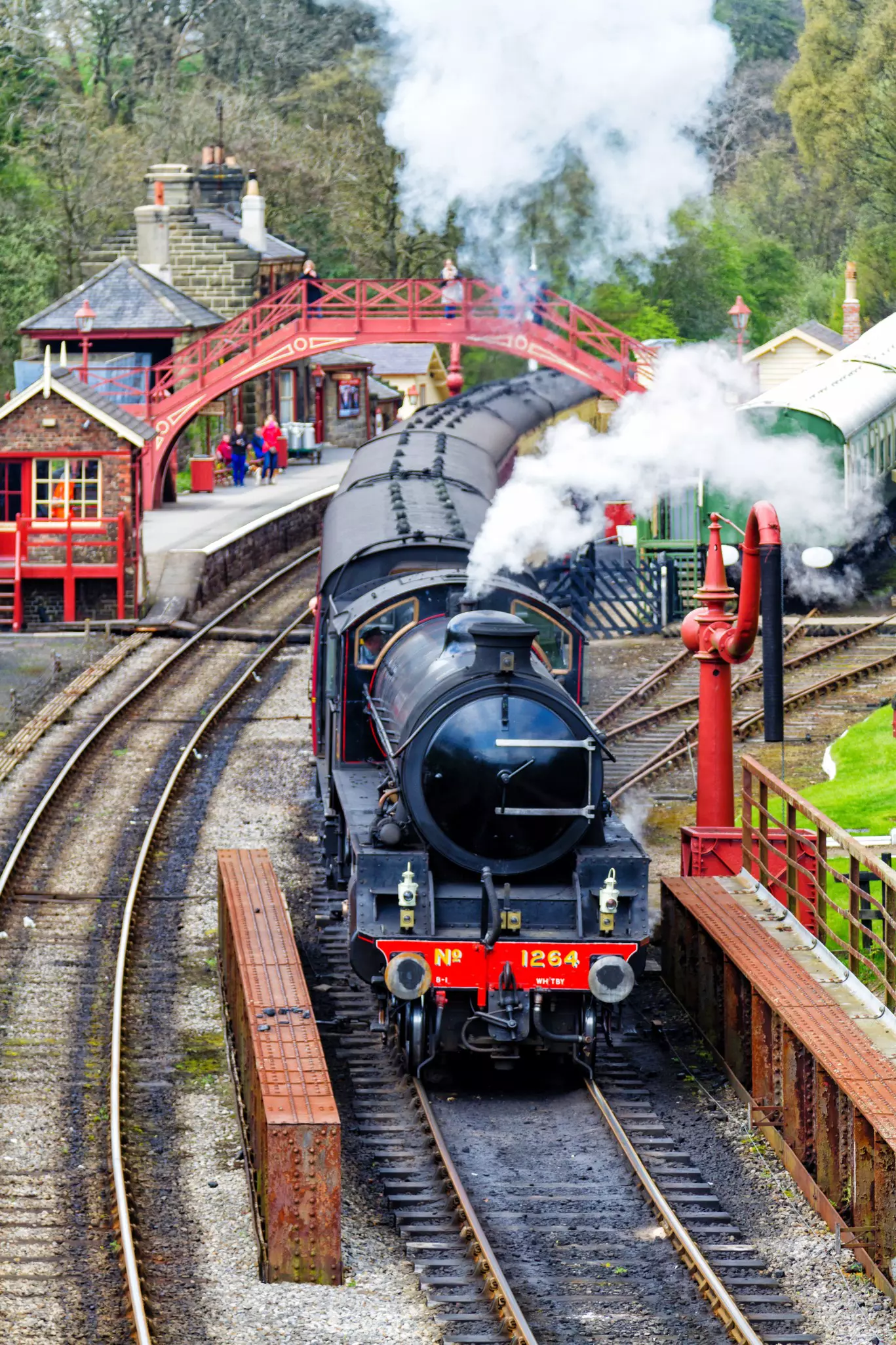 A vintage passenger steam train with carriages at a station in Yorkshire, England 
