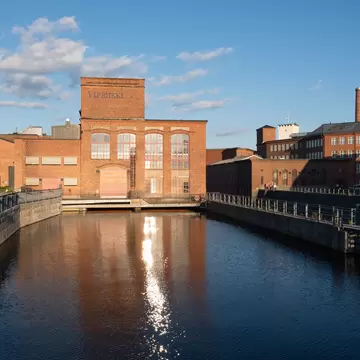 Tampere, Finland - June 2019: Vapriikki Museum, Tampella building. View over Tammerkoski river in warm sunlight