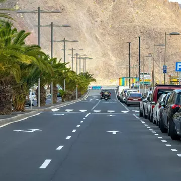 A jeep driving toward a mountain on a road lined with cars