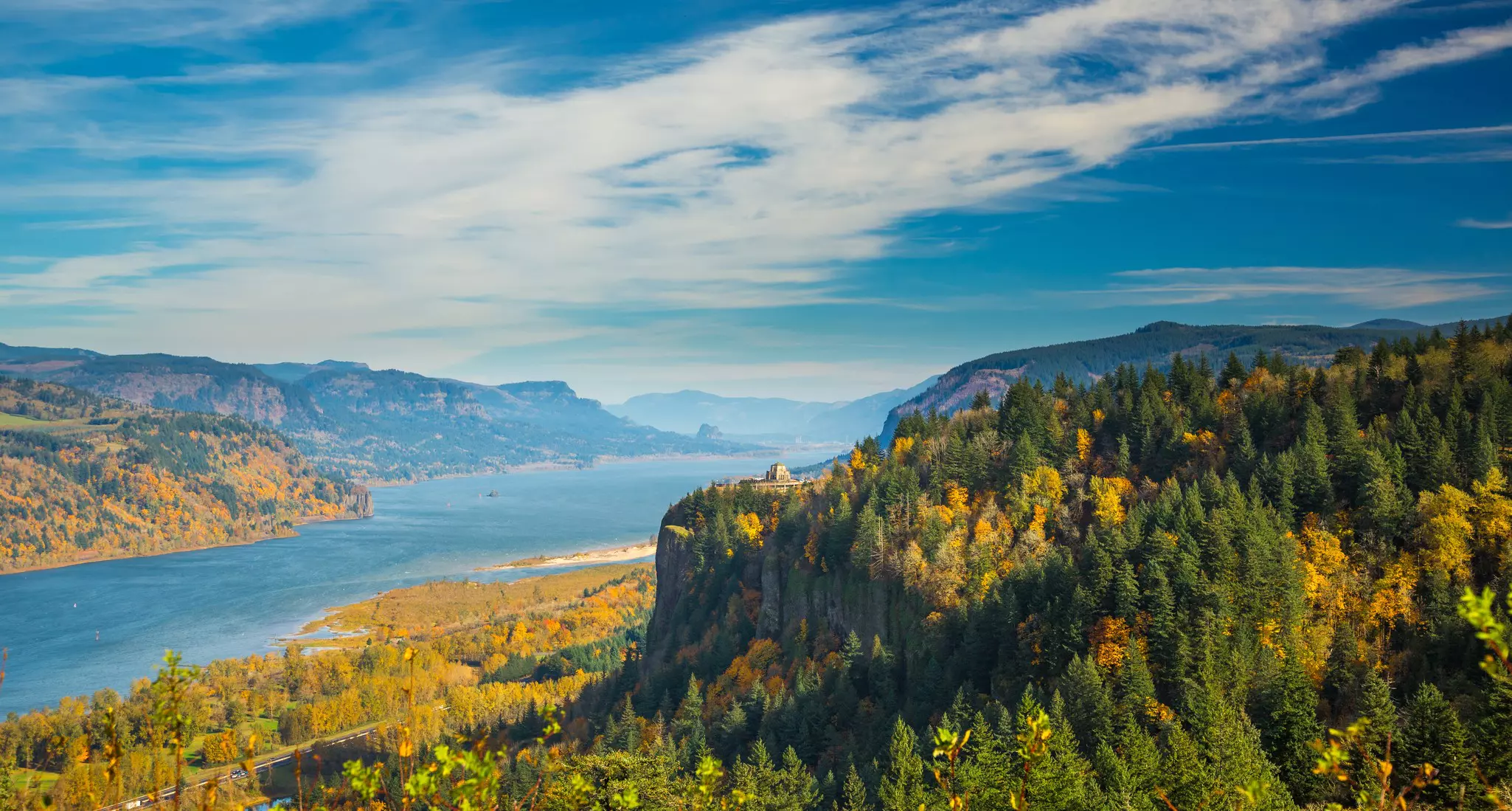 Mountains and shore along a waterway; the trees are in fall colors.