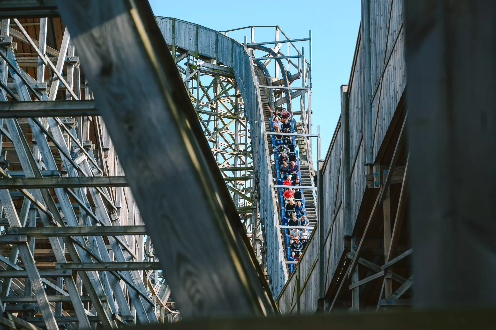 The cars of a roller coaster descend a steep incline.