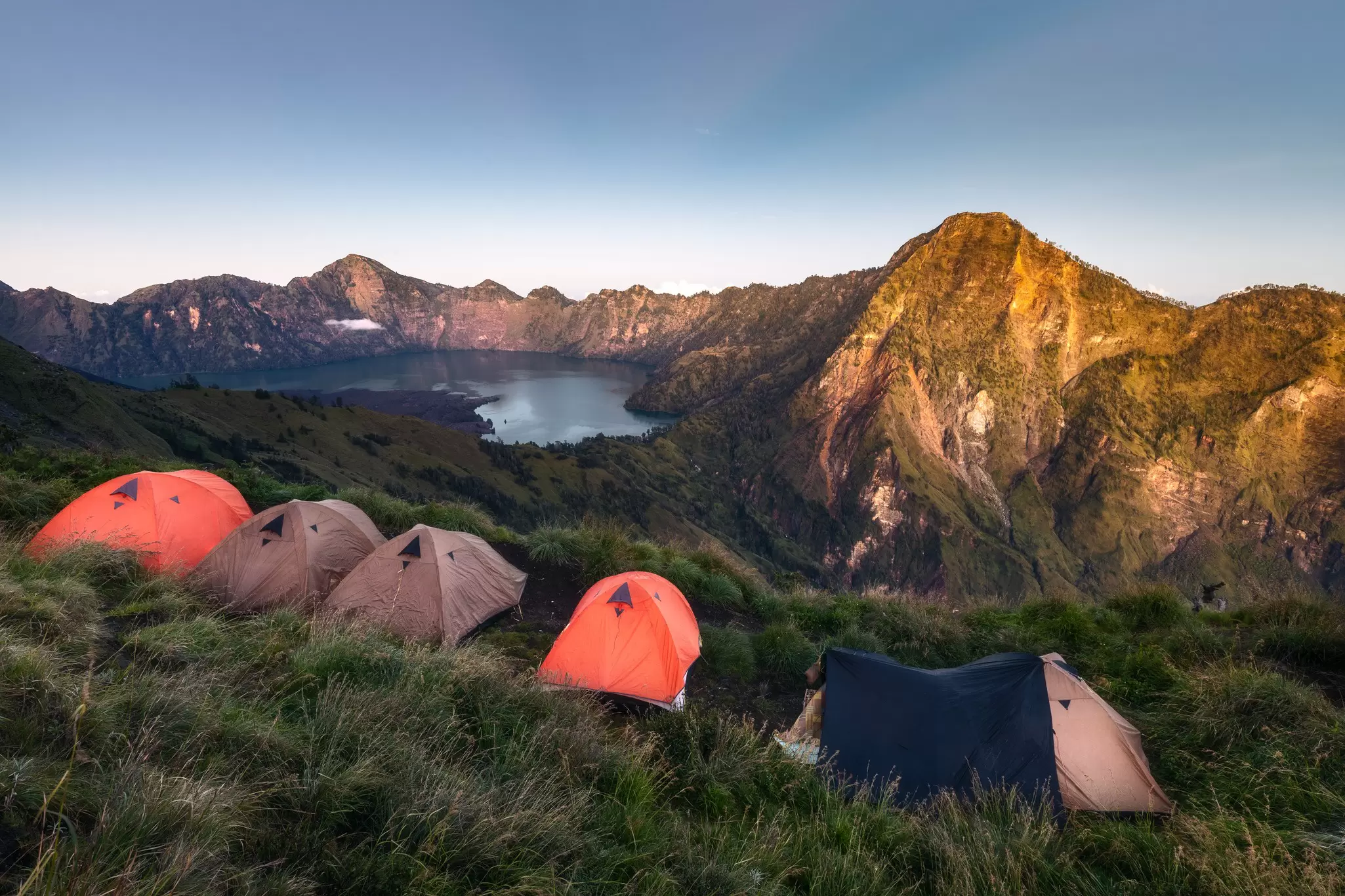 View of tents during sunrise by the rim of a famous Rinjani volcano crater on Lombok island, Indonesia.