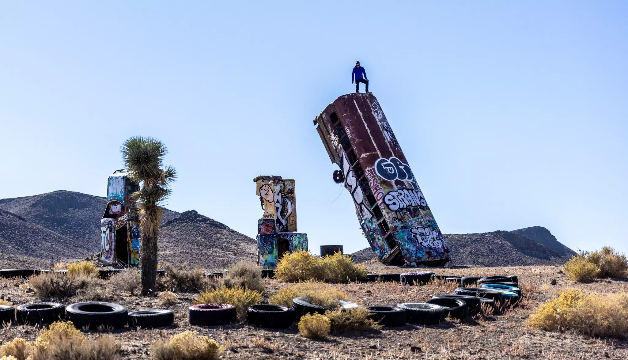 Alex Honnold summits an old bus at the International Car Forest of the Last Church on the outskirts of Goldfield, Nevada