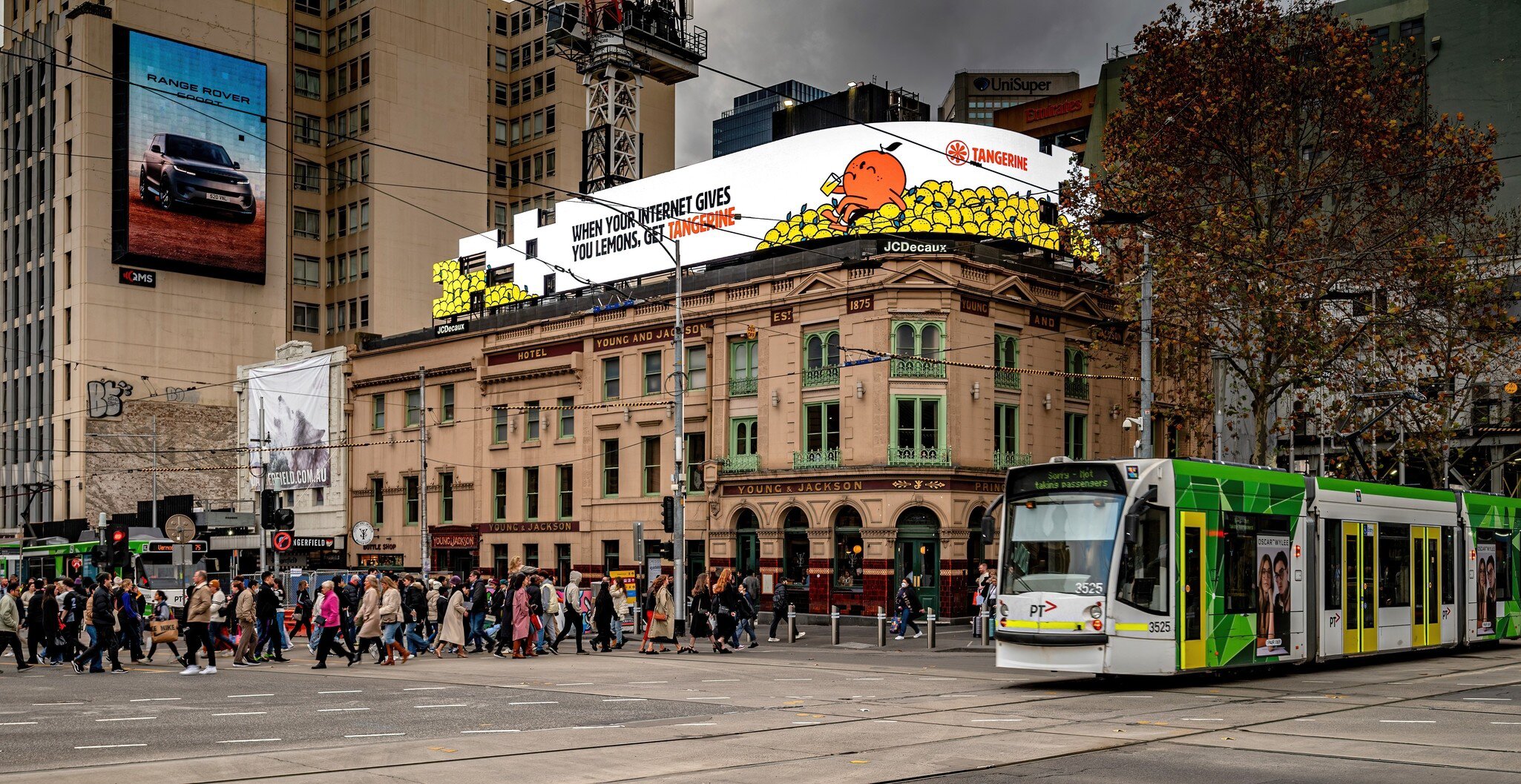 Pedestrians crossing the intersection of Flinders St and Swanston St with historic Young and Jackson's pub on the corner. Melbourne, Australia.