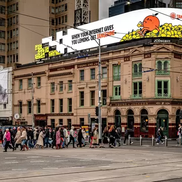 Pedestrians crossing the intersection of Flinders St and Swanston St with historic Young and Jackson's pub on the corner. Melbourne, Australia.