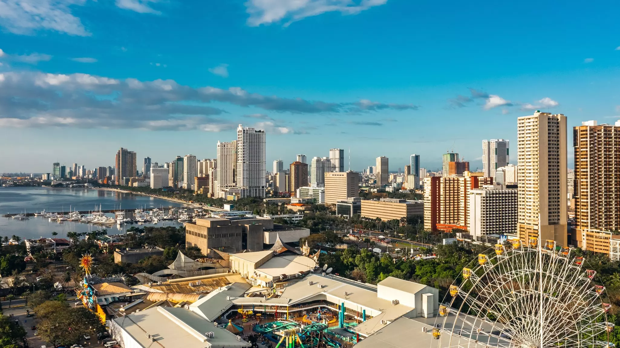 A large city near the ocean, with many high-rise buildings and a Ferris wheel.