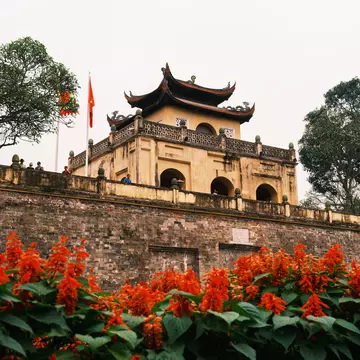 The Thang Long Citadel in Hanoi with red flowers in the foreground.