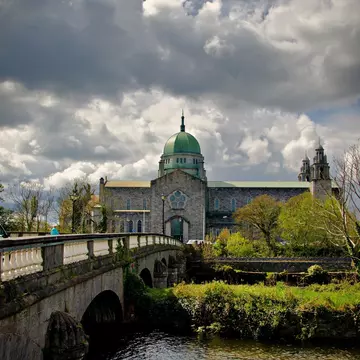 Blue cloudy sky and bridge leading to Galway Cathedral in Galway, Ireland. 