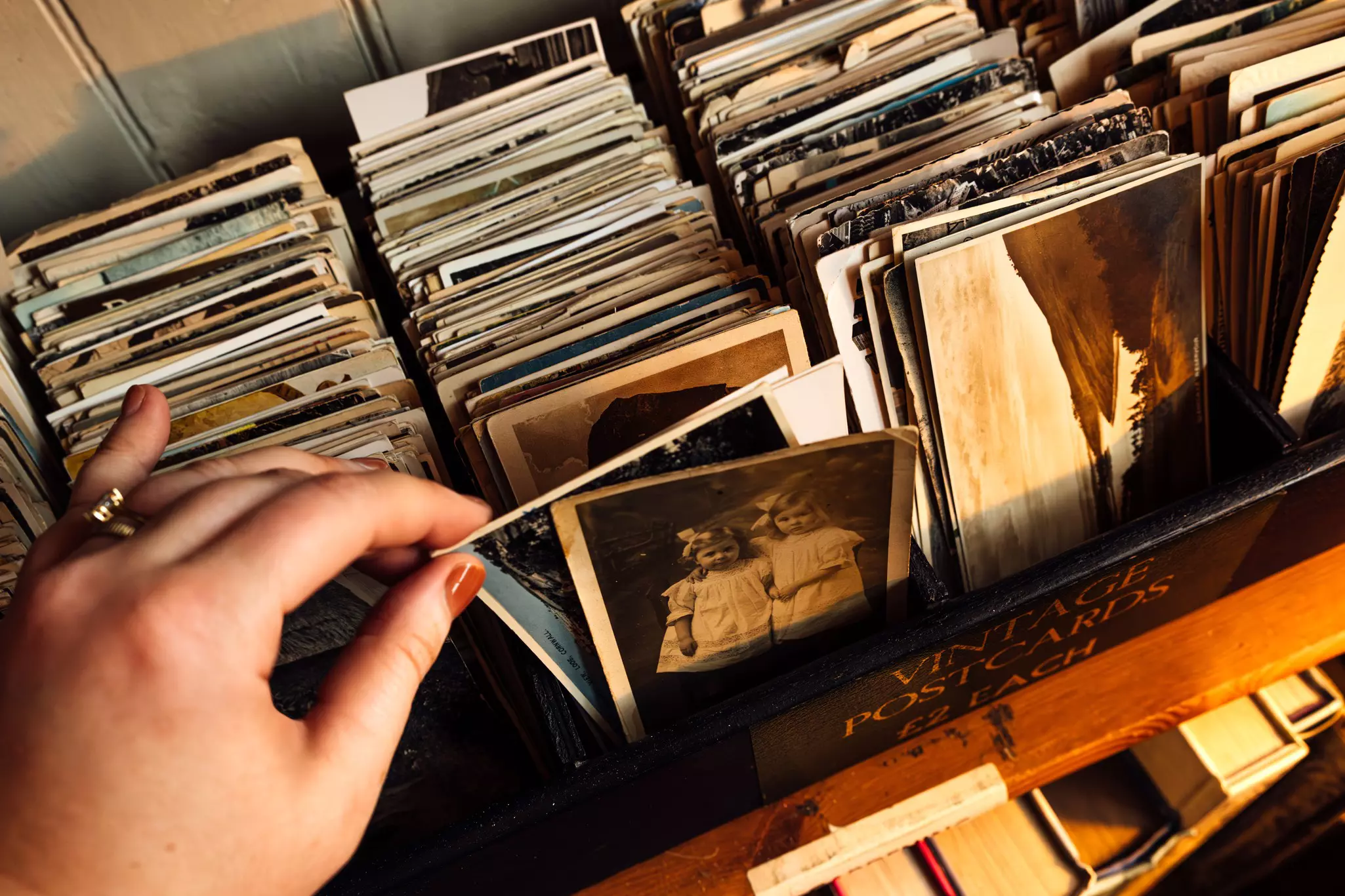 Women sifts through a collection of vintage images at a store.
