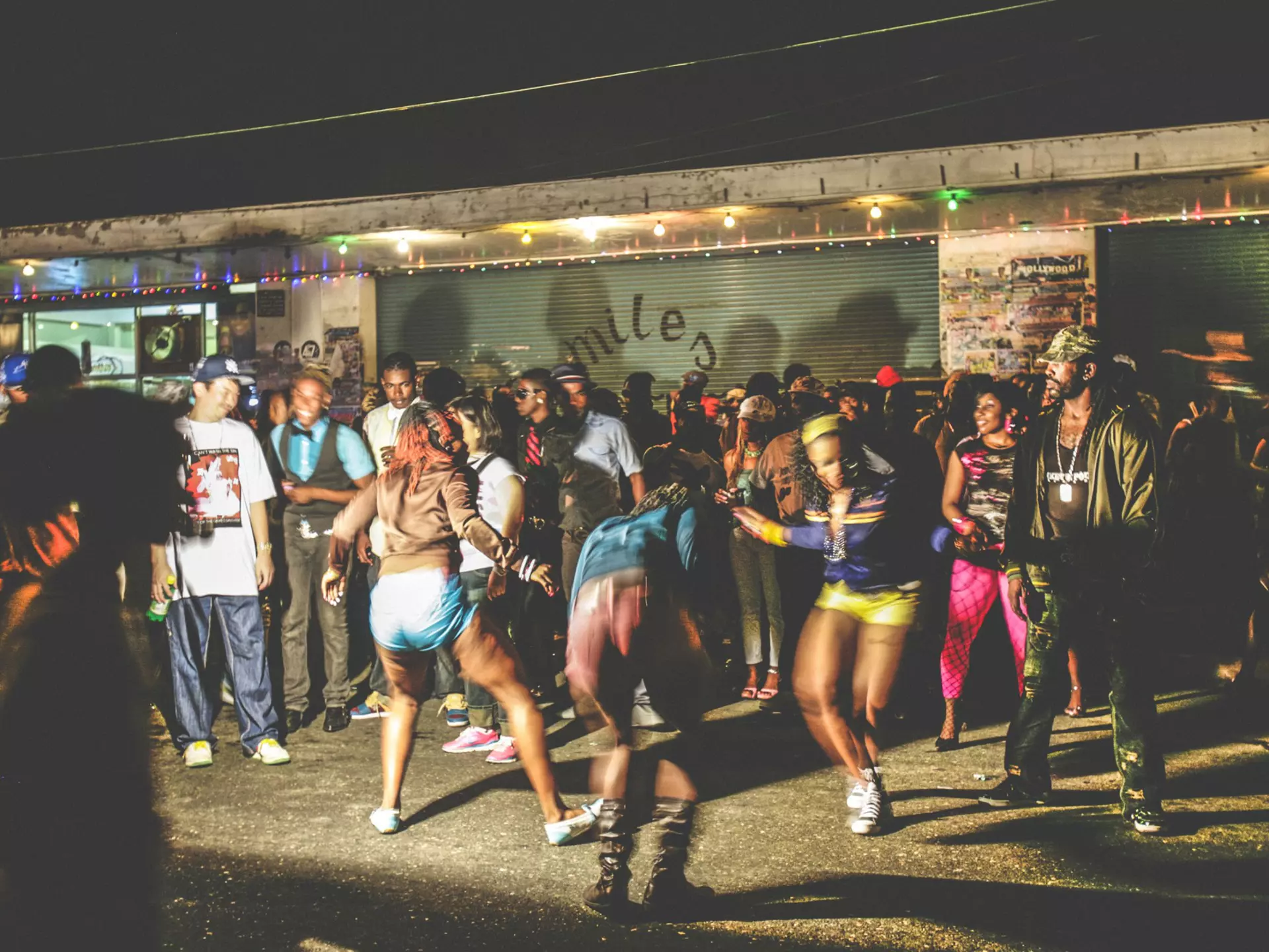 A crowd of dancers on a street in Kingston at night.