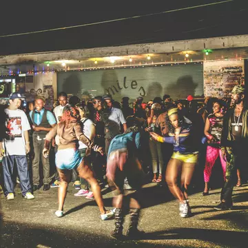 A crowd of dancers on a street in Kingston at night.