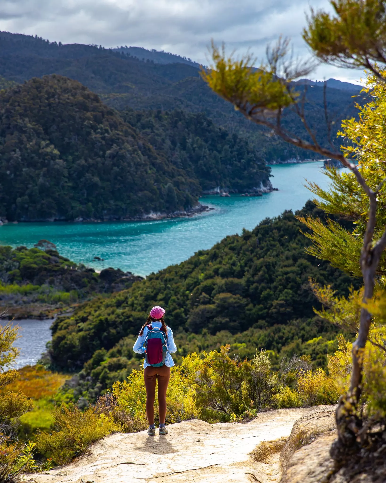 backpacker stands on the hill overlooking Anchorage Bay and Torrent Bay in Abel Tasman National Park - hiking on a famous great walk in New Zealand South Island, License Type: media, Download Time: 2025-09-10T14:34:58.000Z, User: tasminwaby56, Editorial: false, purchase_order: 65050 - Digital Destinations and Articles, job: Online Editorial, client: NZ Best Beaches, other: Tasmin Waby