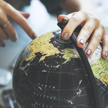 Woman's hand placed on spinning globe