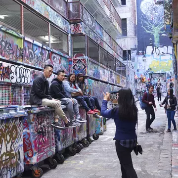 A woman taking pictures of friends in a graffiti-covered lane in Melbourne