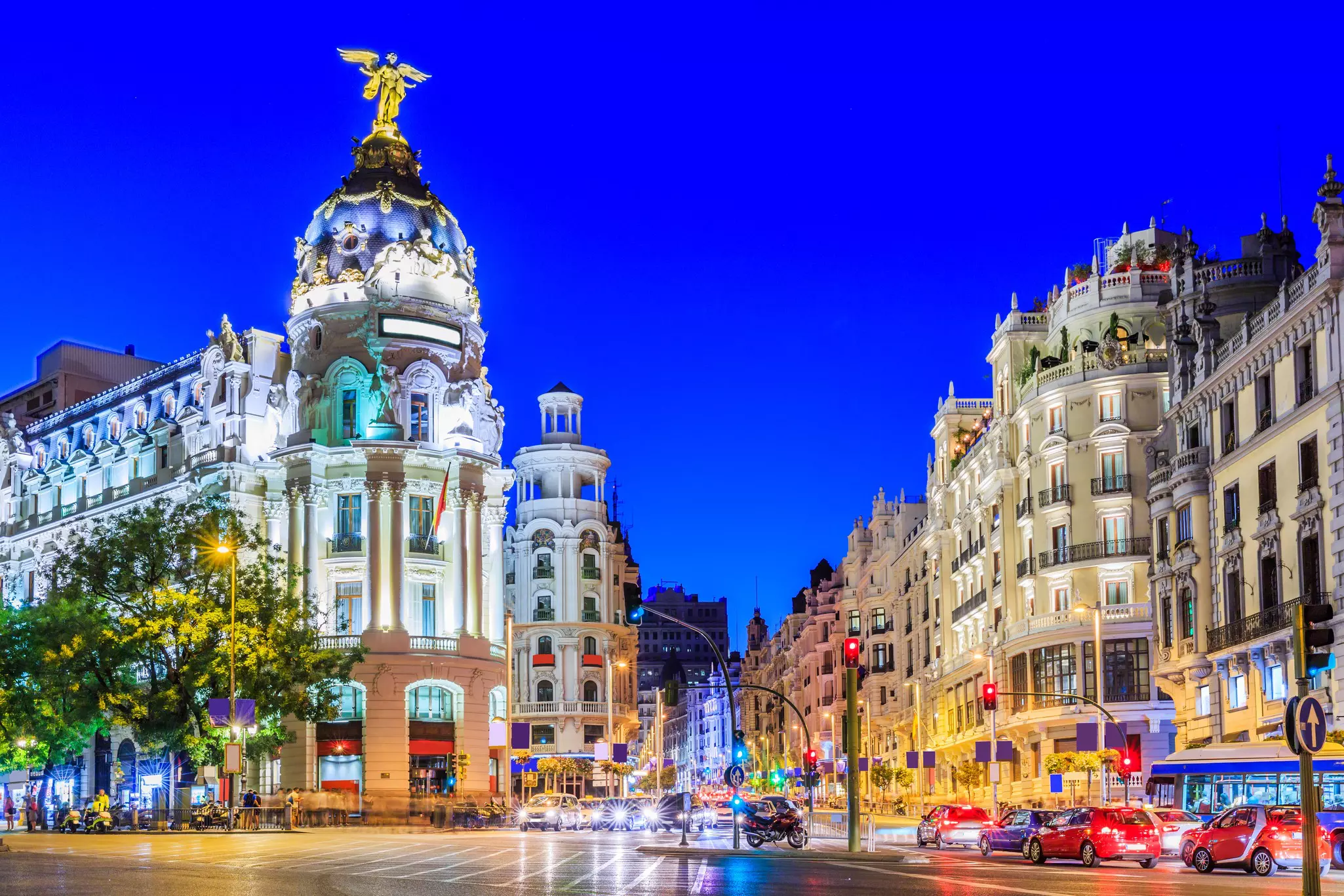 Busy traffic on wide streets in Madrid at dusk.