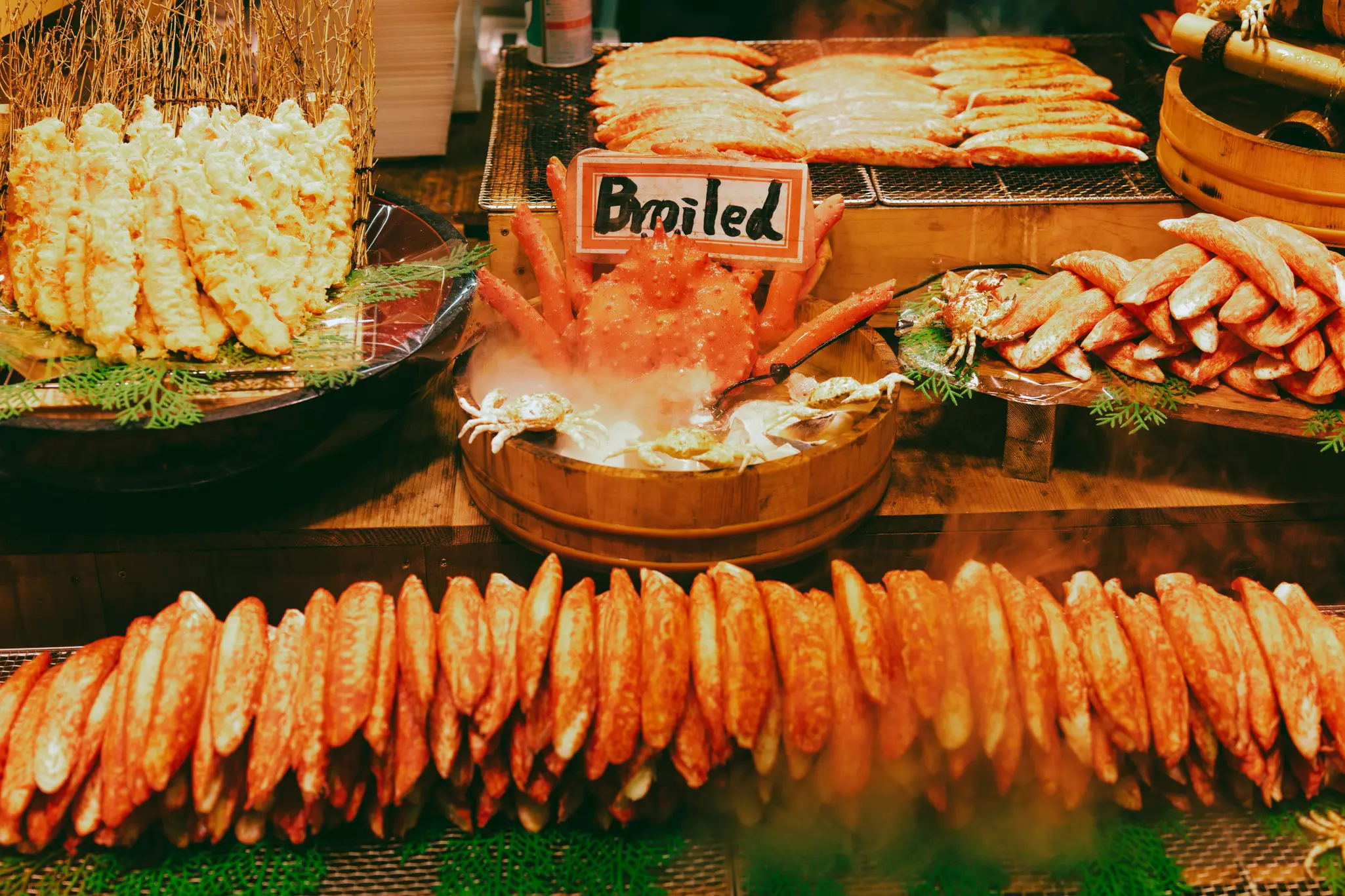 A seafood vendor at Nishiki Market, with items arranged around a crab in a wooden tub. 