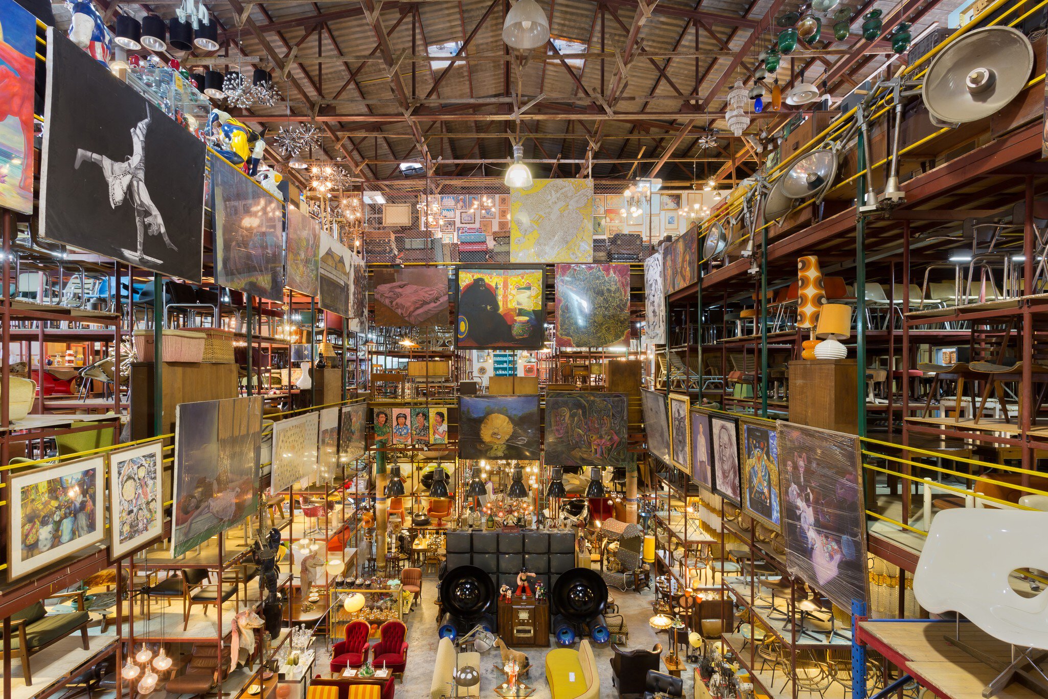 Assorted vintage objects and furniture line ceiling-high shelves at a storage space