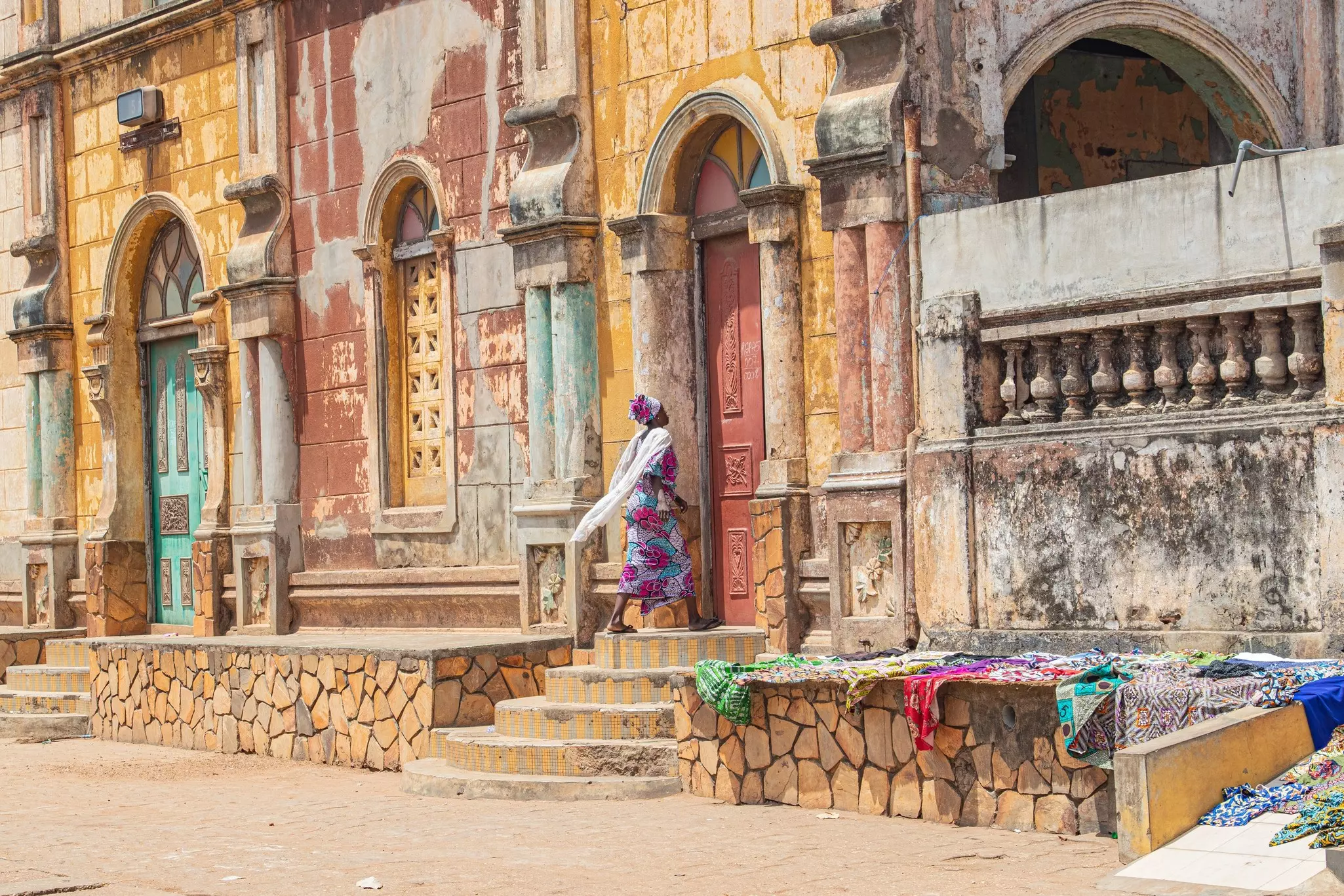A woman walks toward a doorway of building with an elaborate facade covered with colonial-style ornamentation.