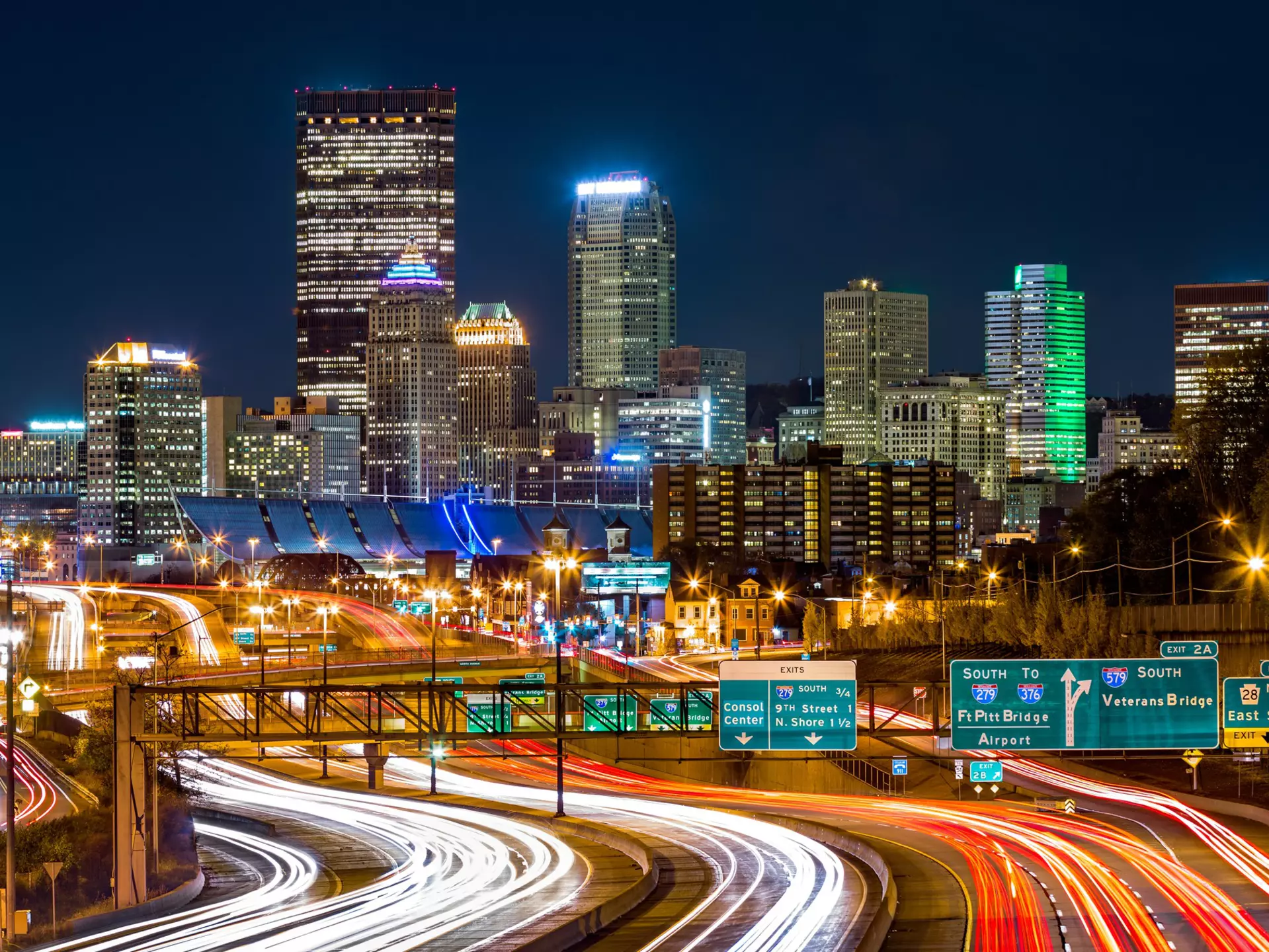 The Pittsburgh skyline by night, you can see the bright lights of cars driving on I-279 parkway