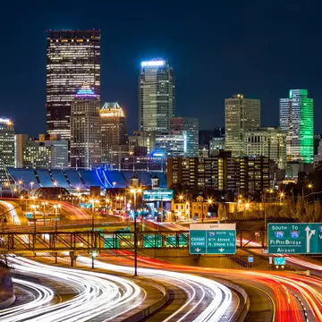 The Pittsburgh skyline by night, you can see the bright lights of cars driving on I-279 parkway