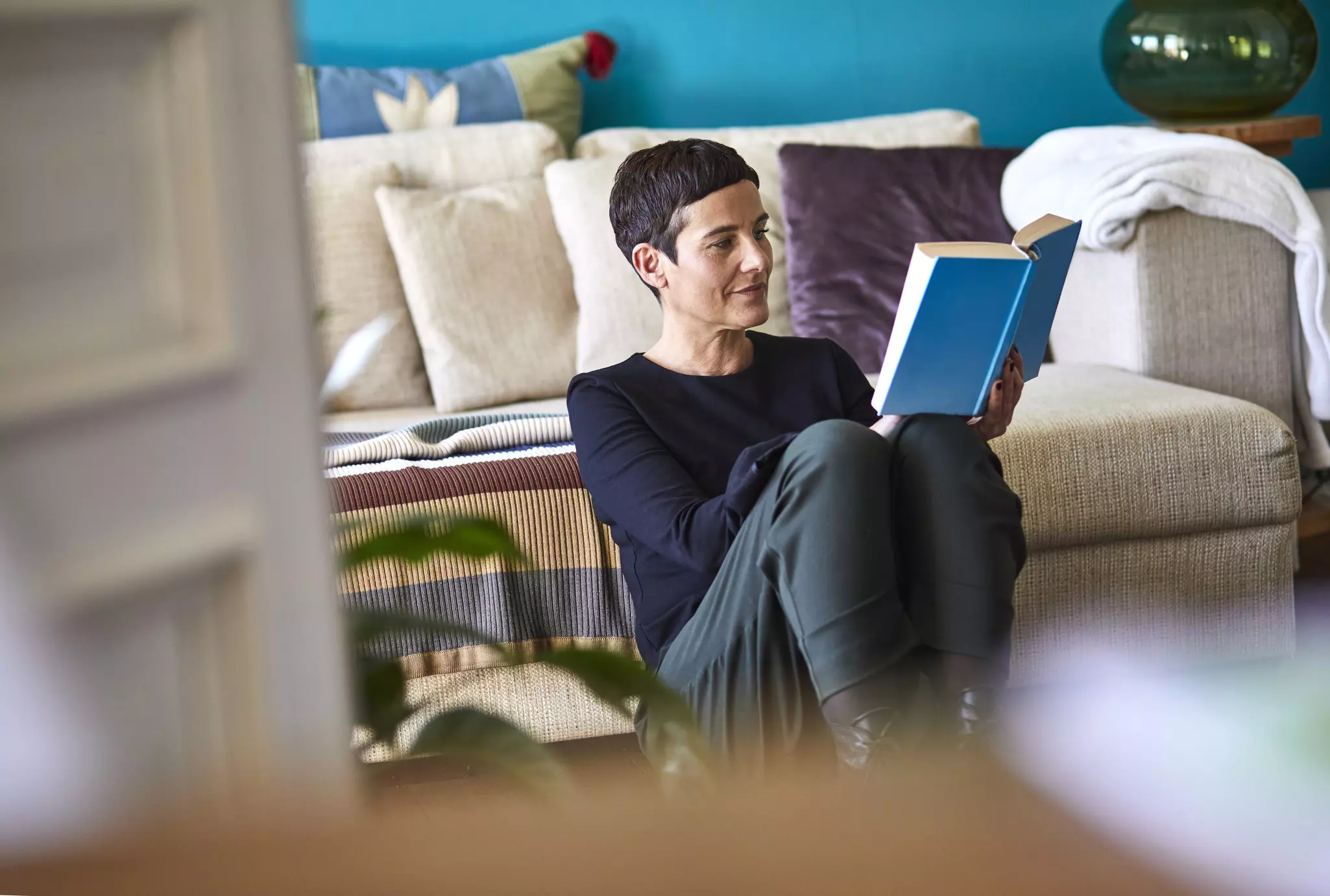 A woman relaxes at home with a book © Oliver Rossi / Getty Images