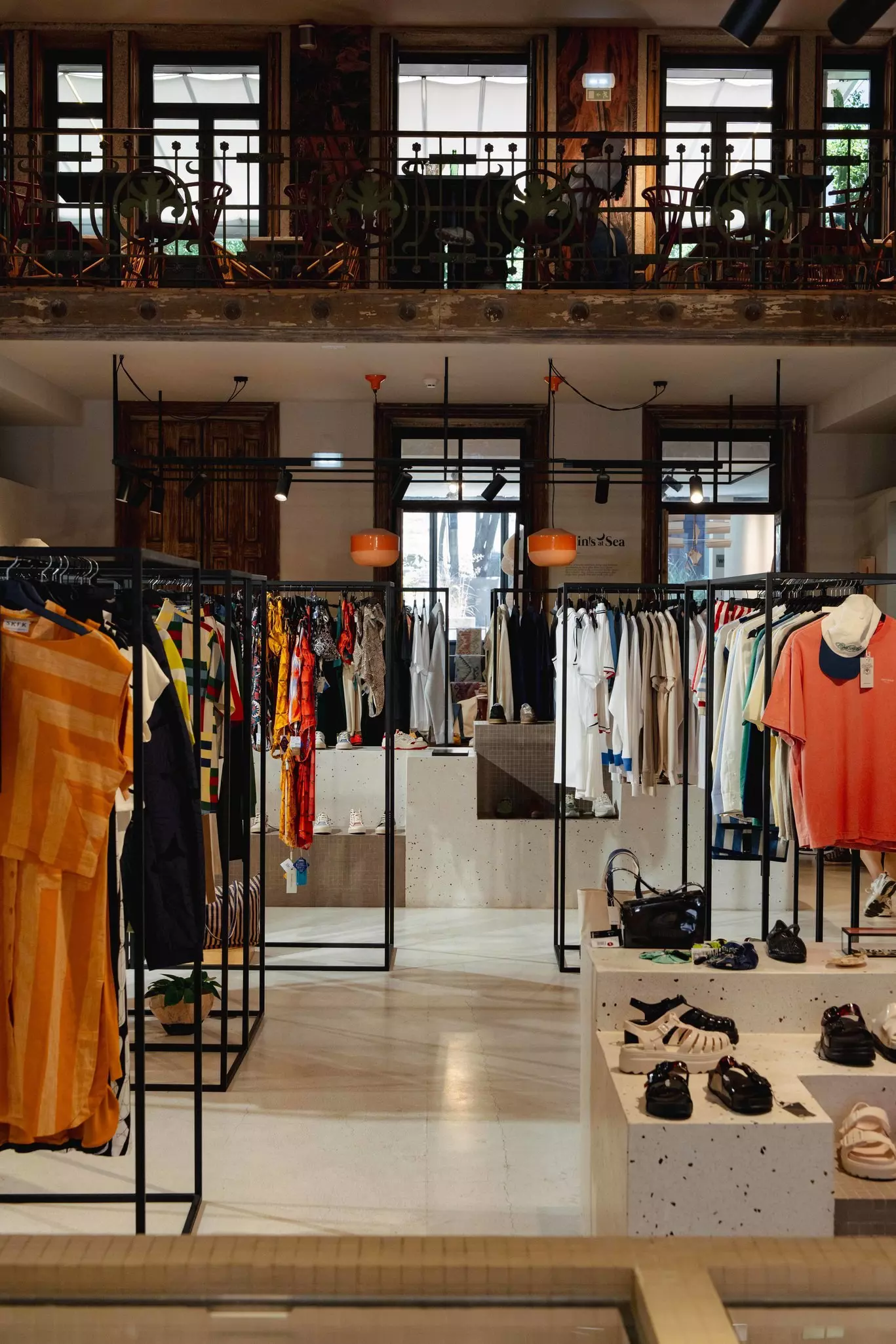 Clothes hacking on racks and shoes sitting on blocks in a store.
