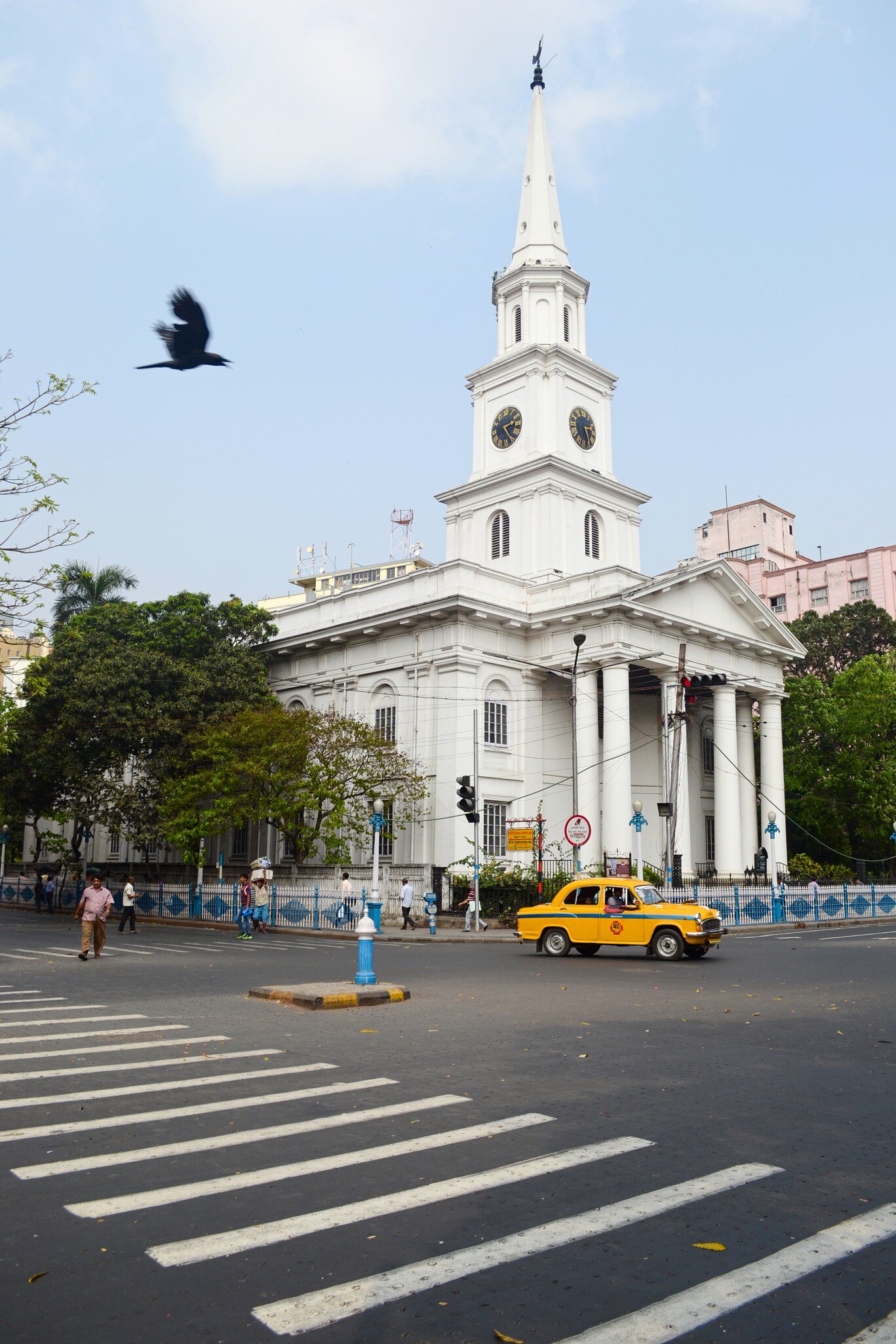 Yellow taxi cab on the crossroad in front of old catholic St. Andrew's church in Calcutta, West Bengal, India.
