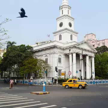 Yellow taxi cab on the crossroad in front of old catholic St. Andrew's church in Calcutta, West Bengal, India.