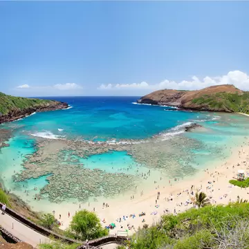 People head out into the turquoise waters of a large cove with shallow reefs