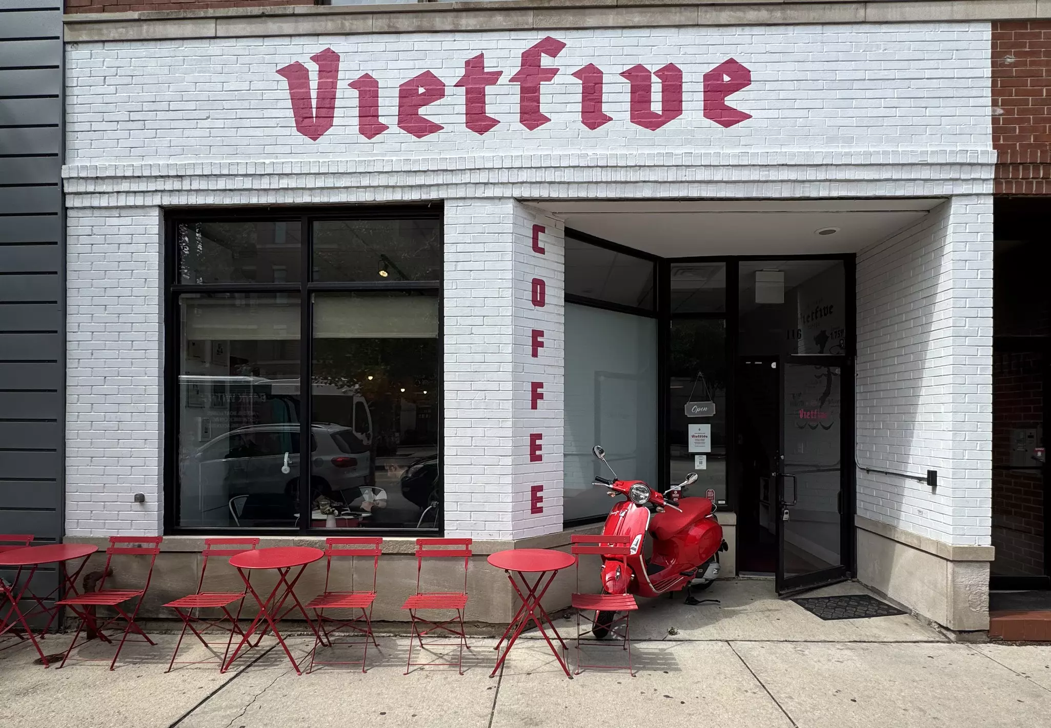 A white storefront, with red chairs and tables in front and "Vietfive Coffee" painted in red.