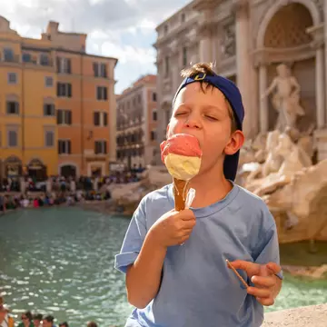 Boy eating gelato near the Trevi Fountain in Rome, Italy