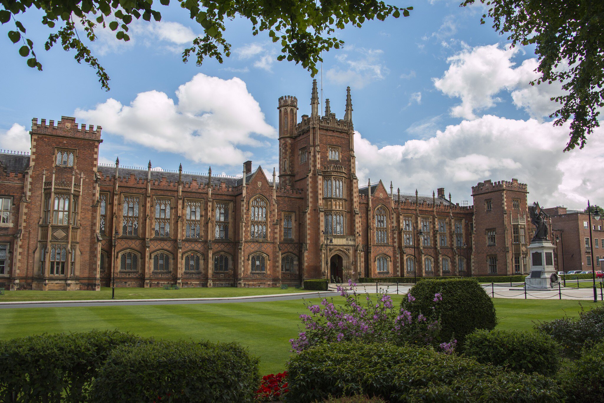 Exterior of Queens University in Belfast, Ireland. Trees,  bushes, and lawn surrounding.