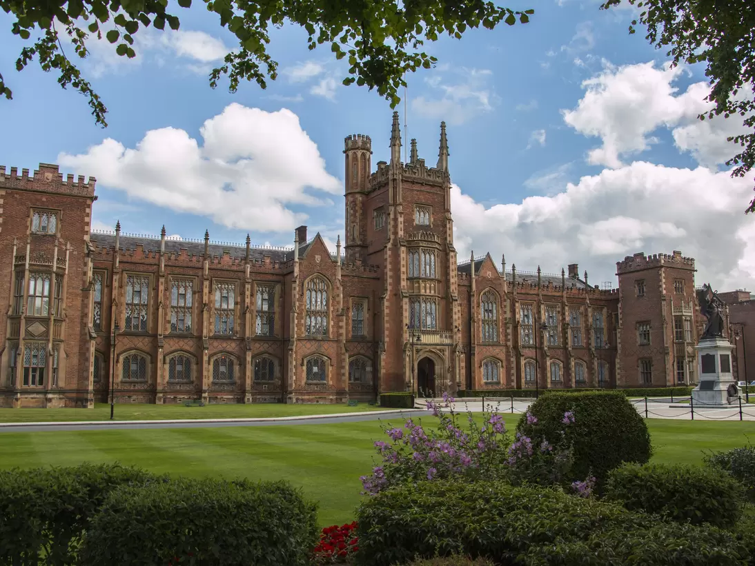 Exterior of Queens University in Belfast, Ireland. Trees,  bushes, and lawn surrounding.
