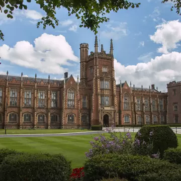 Exterior of Queens University in Belfast, Ireland. Trees,  bushes, and lawn surrounding.