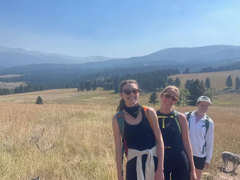 Three hikers on a trail through a field