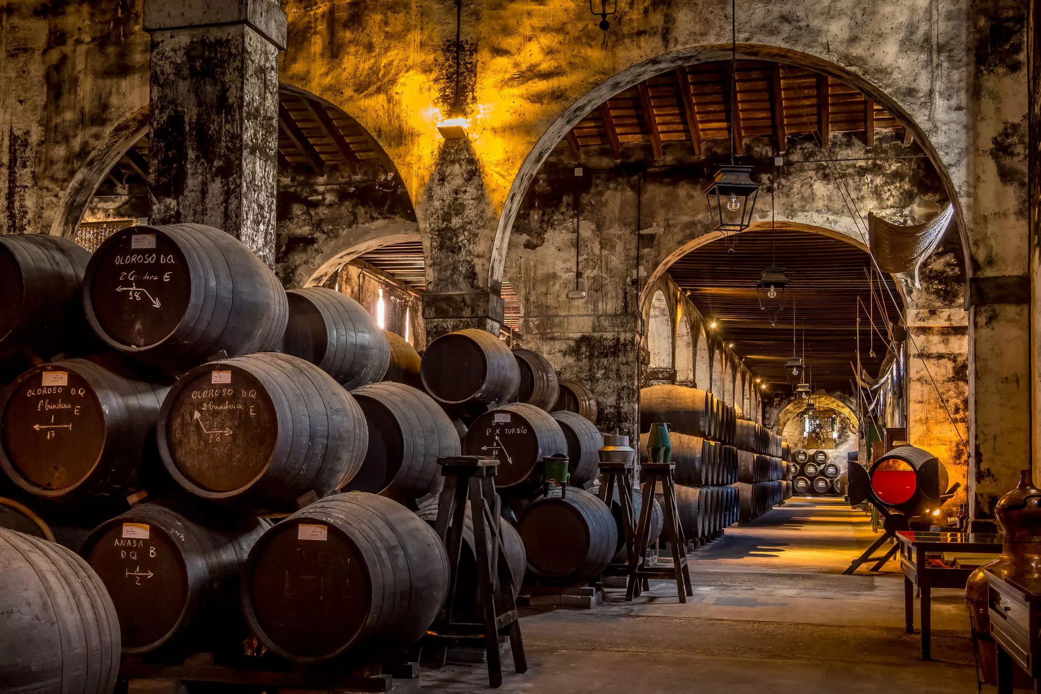 A vast cellar stocked with huge wooden barrels piled on their sides on top of each other.