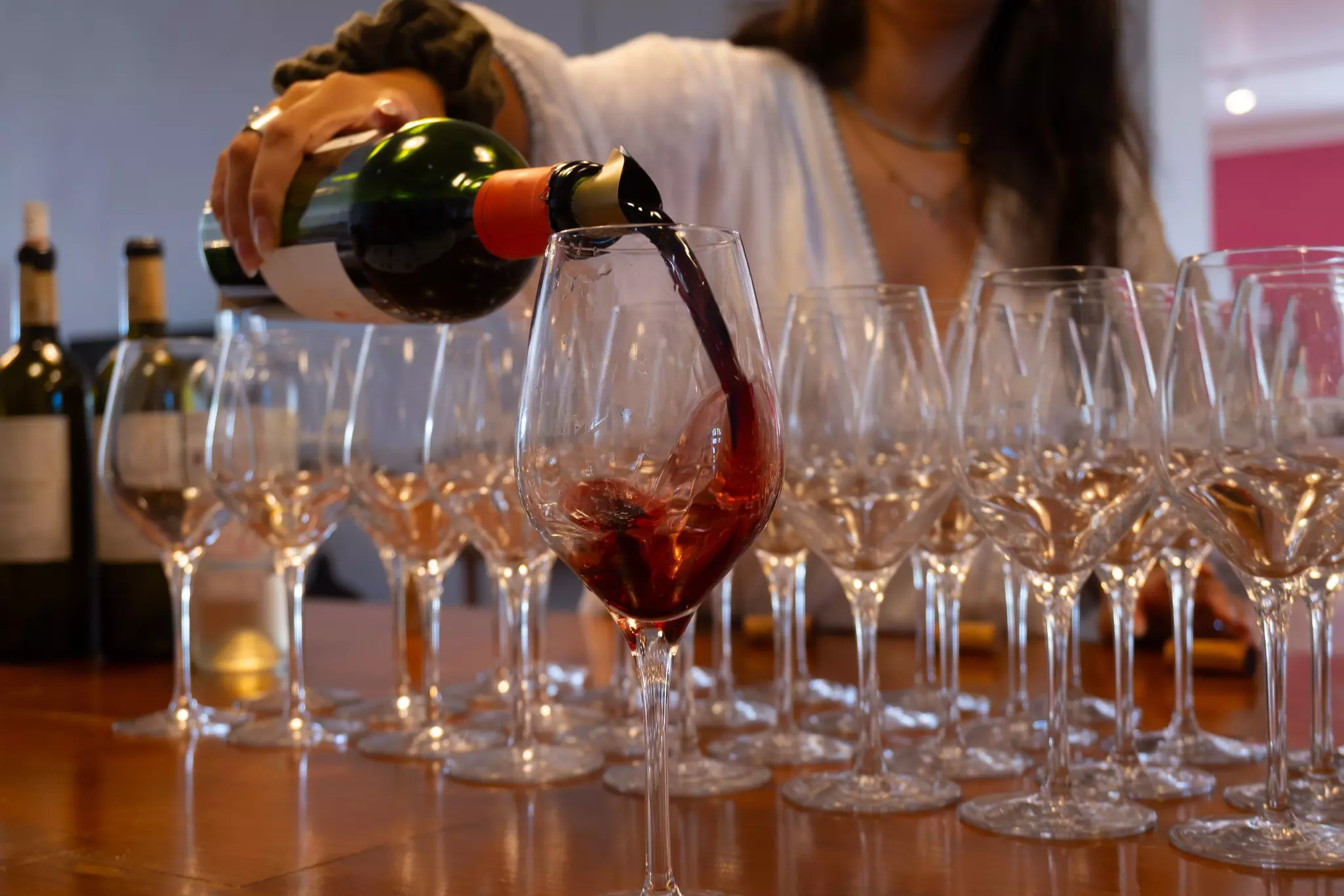 A sommelier pours red wine into a glass at a wine tasting.