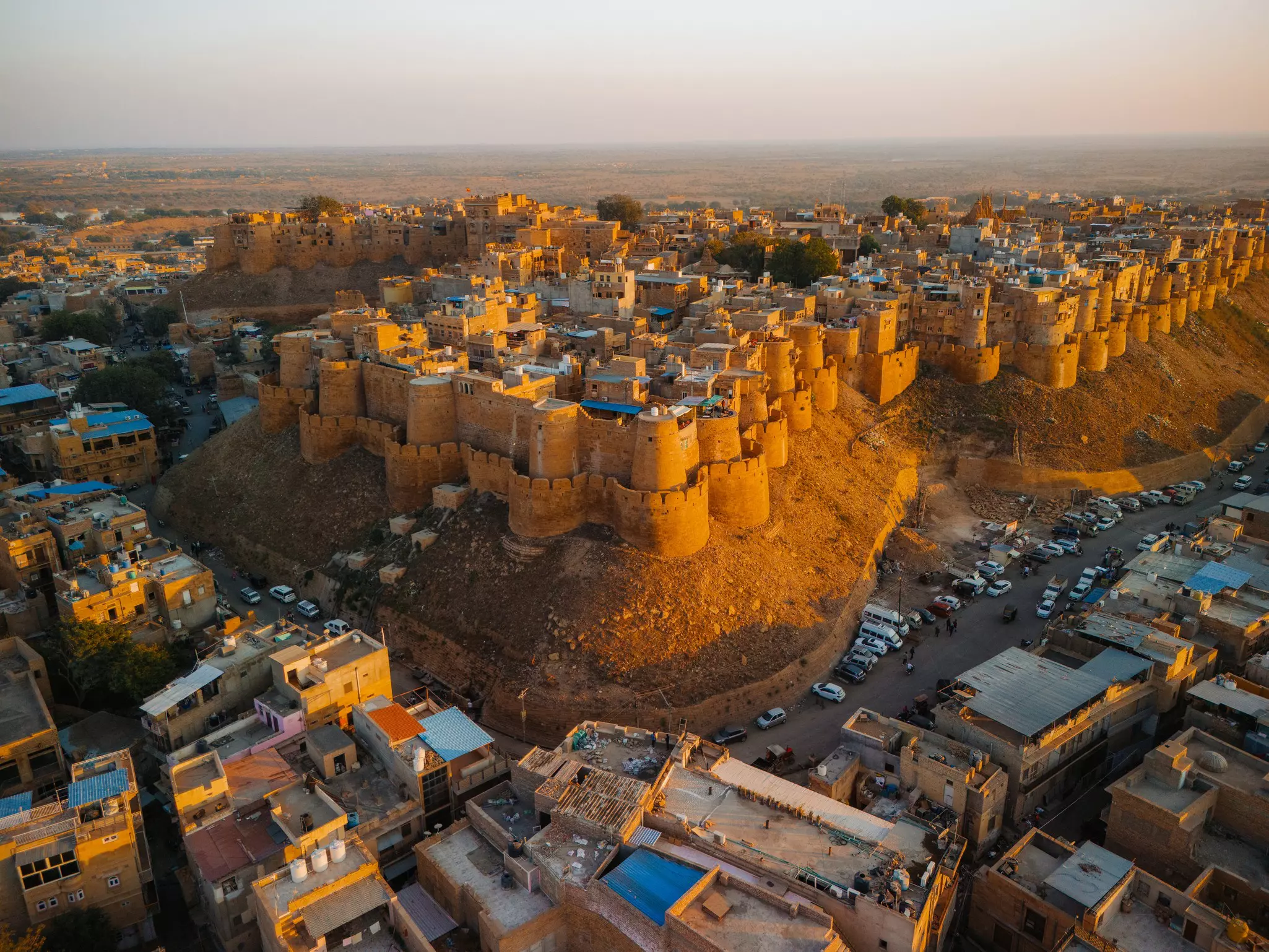 An aerial view of a massive fort with many turrets, rising above a sprawling city.