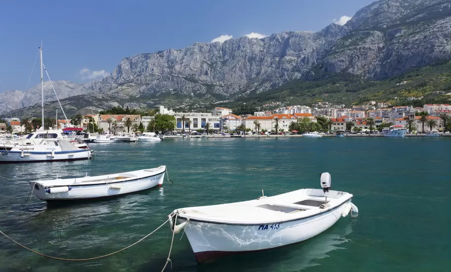 Makarska harbour with small white boats, one marked MA 413, below the rocky Biokovo mountains on Croatia's coast