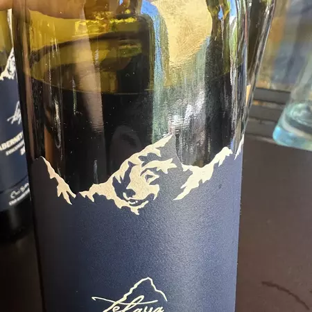 Wine bottle with blue label with white mountains on it. The white lines outline the shape of a dog's face.