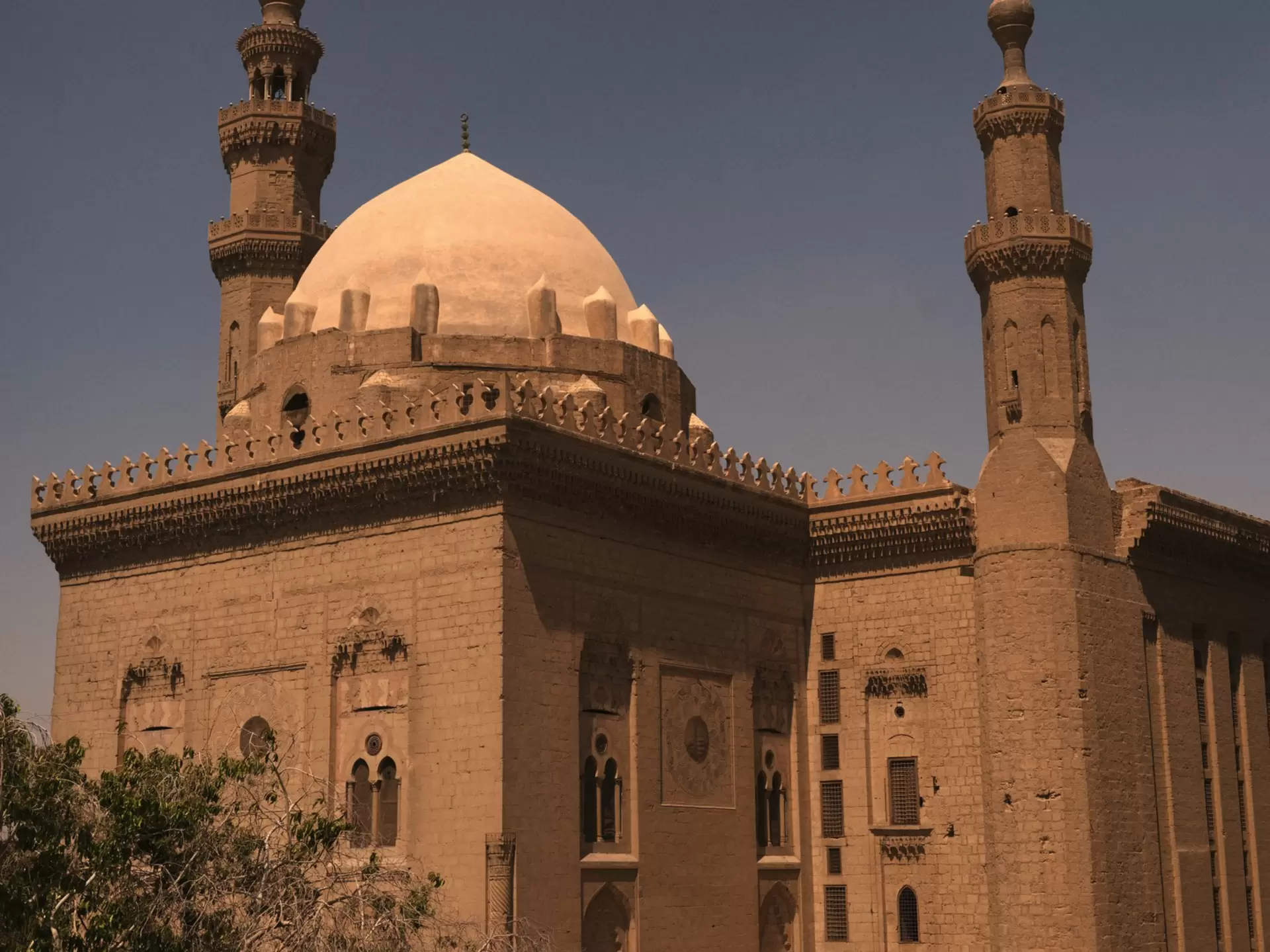 The exterior of a mosque in Cairo, Egypt with two columns and a dome. 