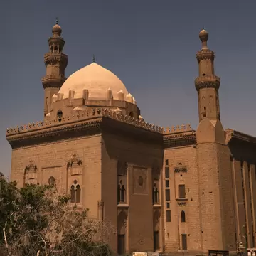 The exterior of a mosque in Cairo, Egypt with two columns and a dome. 