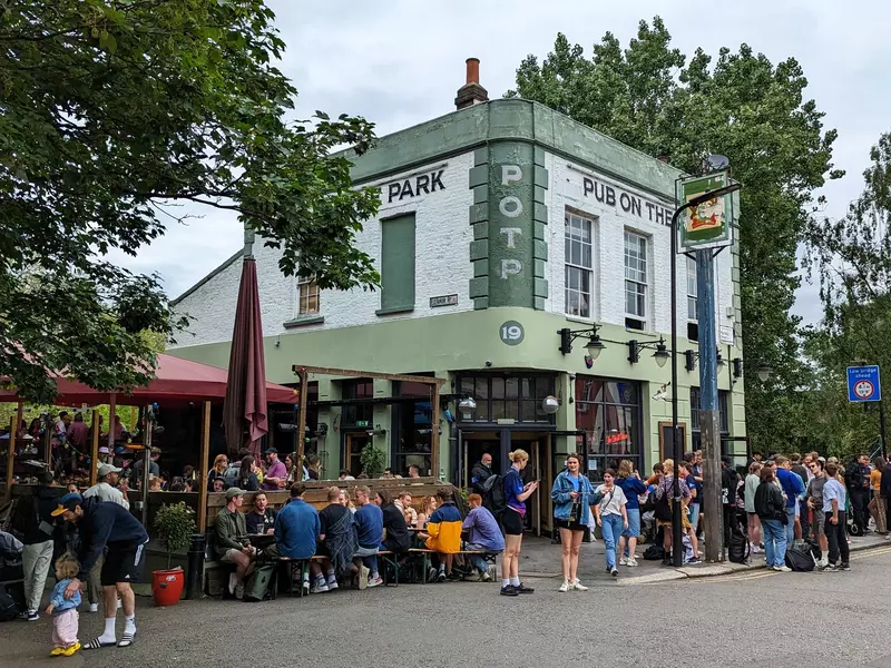 Groups of people sit and stand outside a pub