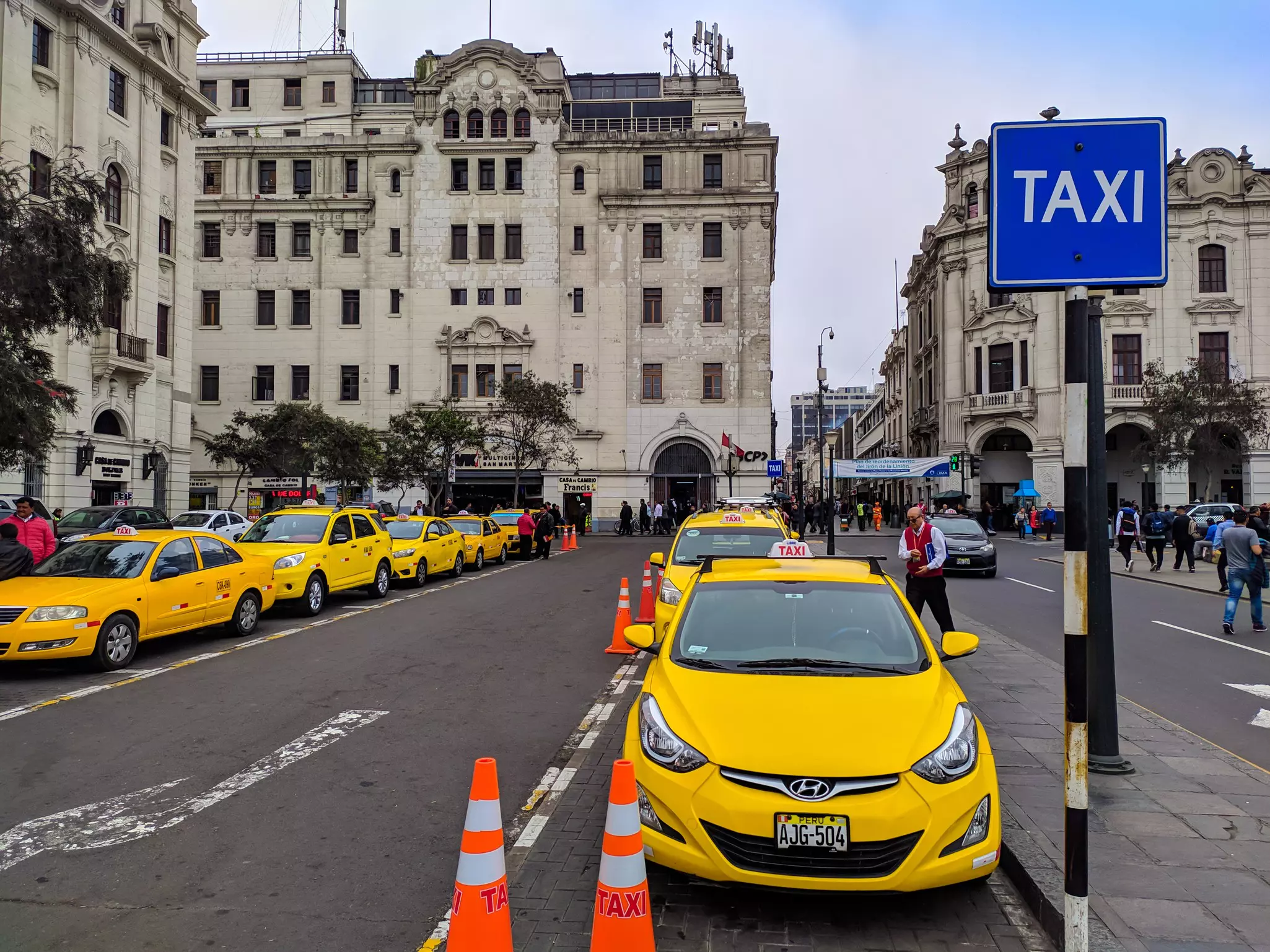 Two lines of taxis are pictured along the curbs of a city square. 