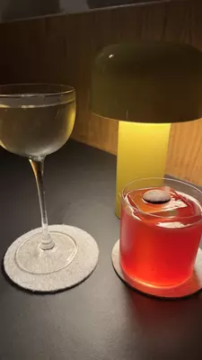 Close-up of two cocktails on a table with a lamp nearby.