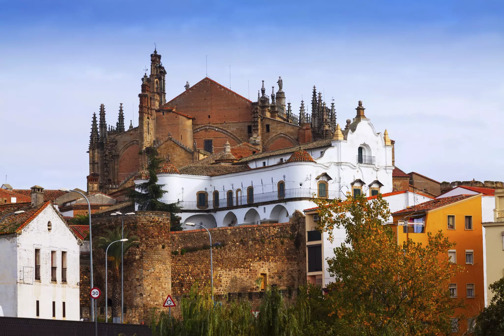 Old stone houses and a cathedral in the background against a blue sky.